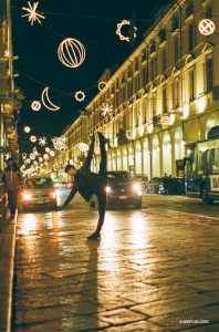 Танцор принял изящную позу на фоне волшебных огней инсталляции Luci d’Artista в Турине.